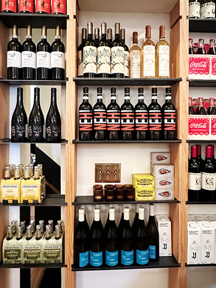 Open wine shelves and grocery storage inside Manita, a thoughtfully designed café and bar in Toronto’s Rosedale neighborhood.