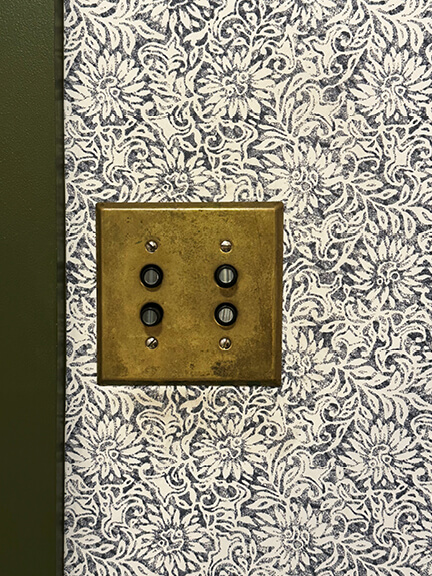 Vintage brass light switch on a neutral wall at Nickey Kehoe’s LA showroom with subtle hardware details