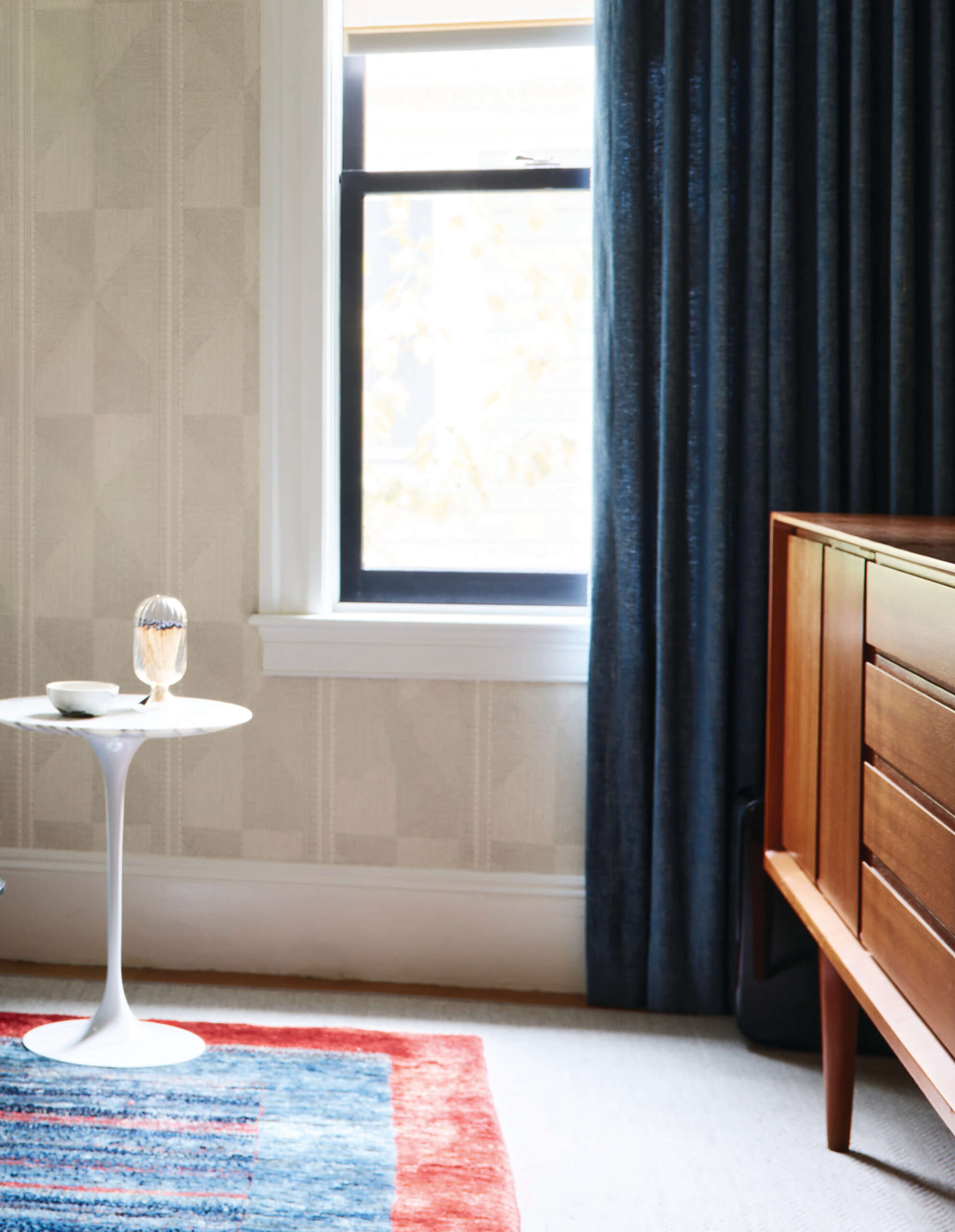 Open floor plan problems solved with layered rugs, mid-century furniture, and Pierre Frey wallpaper in this Brookline space.