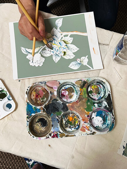 Gracie showroom in LA with a master artist giving a live painting demonstration of custom hand-painted wallpaper