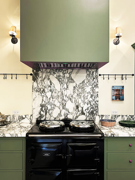 Green kitchen cabinets with marble backsplash at Nickey Kehoe’s LA showroom featuring custom millwork and natural stone finishes