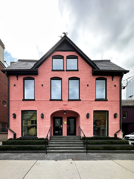 Pink historic building in Yorkville, Toronto, with black doors and windows—modern retail design layered onto a preserved facade for a fashion brand