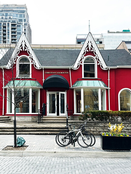 Red Victorian building in Yorkville, Toronto, home to Christian Louboutin’s Canadian storefront, blending historic retail design with bold color