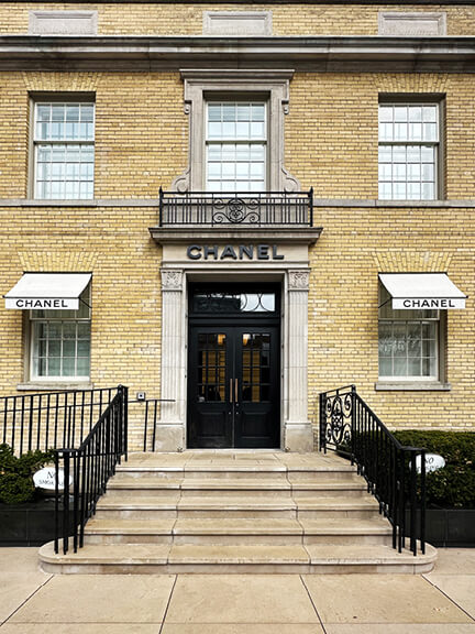 Restored yellow brick historic building in Toronto with crisp black doors, now home to Chanel’s modern retail design in a preserved architectural setting