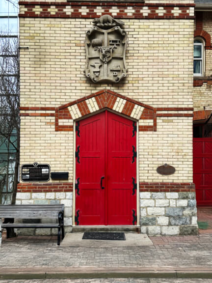 Red door on a historic Yorkville firehouse in Toronto with yellow brick and arched openings, still in use today.