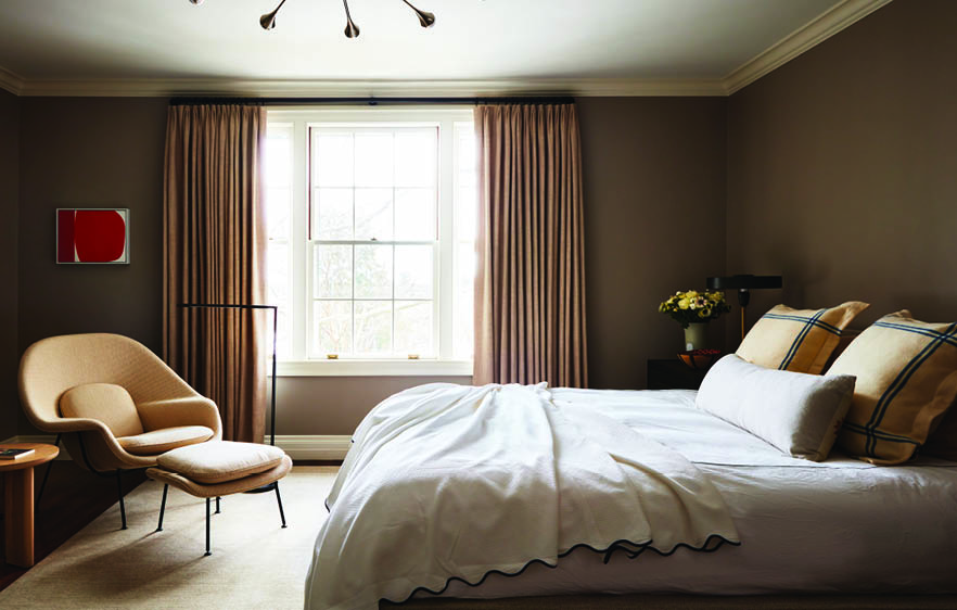 Open floor plan problems solved with scaled furniture, drapery, and rugs in a taupe bedroom within a historic home.