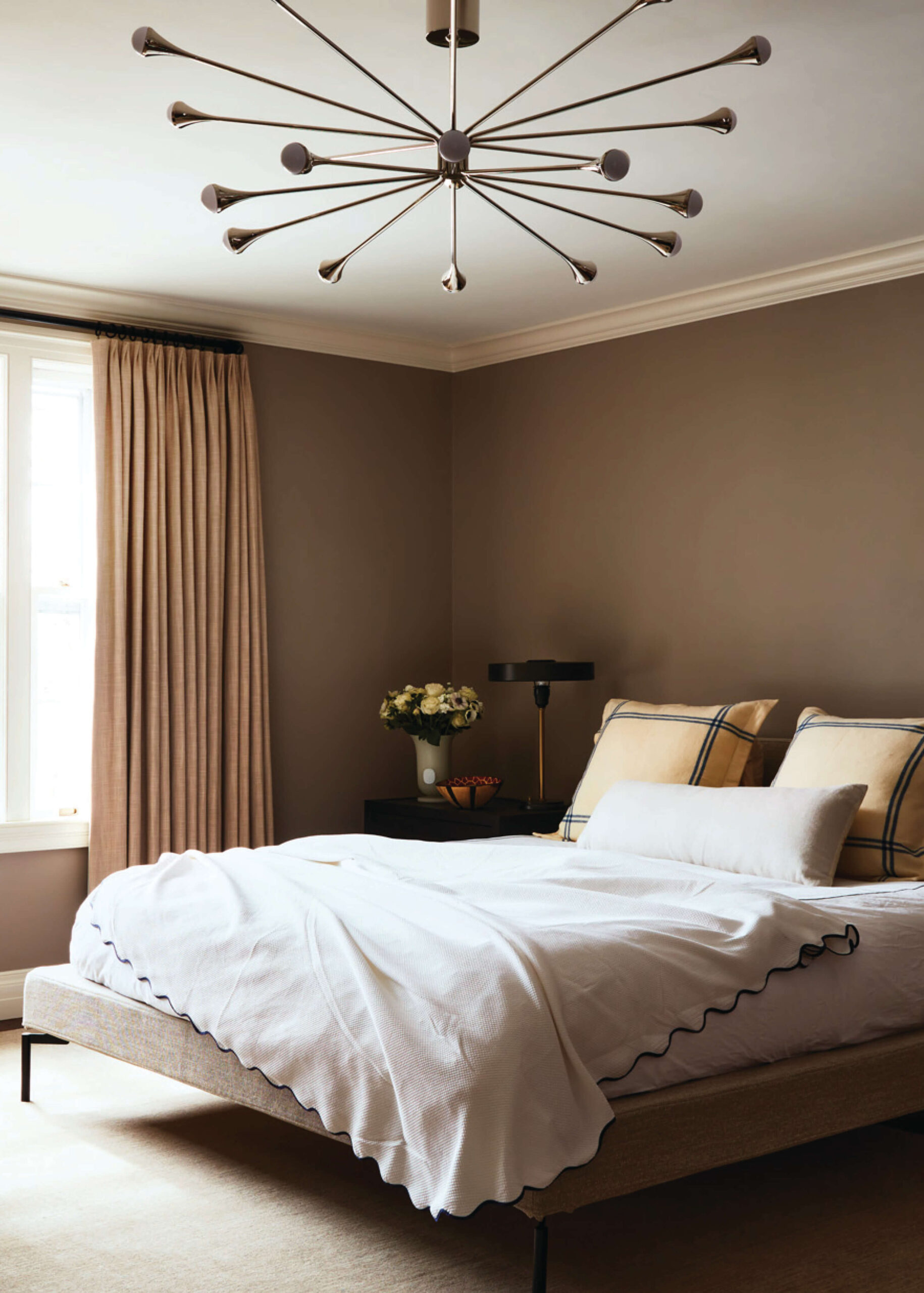 Cozy Concord primary bedroom with retro light fixtures and upholstered bed in a historic home design.