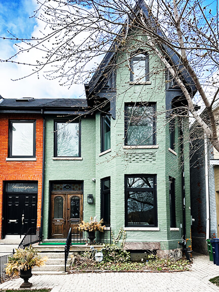 Light green painted brick exterior of a historic Summerhill home in Toronto, with original trim and understated detailing.