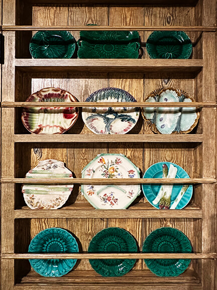Ken Fulk showroom in LA with faux wood walls and built-in shelving displaying ceramics in a moody, layered retail space