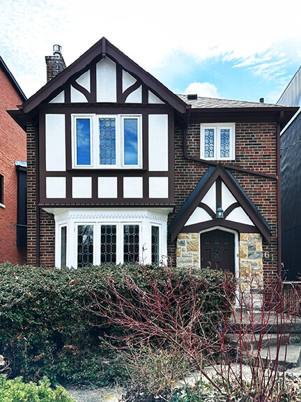 Half-timbering and steep rooflines highlight the Tudor-style facade of a historic home in a residential Toronto neighborhood.