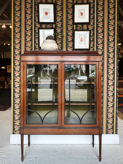 Vintage furniture with wallpaper and art in Nickey Kehoe’s LA showroom featuring layered decor and custom pieces