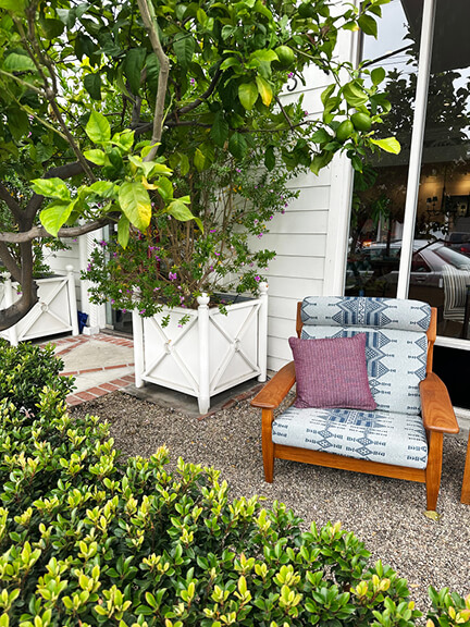 Peter Dunham outdoor furniture at Hollywood at Home with light blue upholstery and a purple throw pillow in a California modern setting