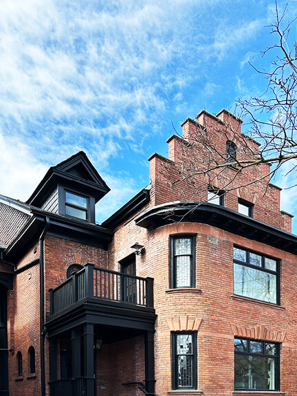 Stepped terrace roofline on a historic brick home in Toronto’s Annex, featuring black-painted architectural details and preserved 19th-century character