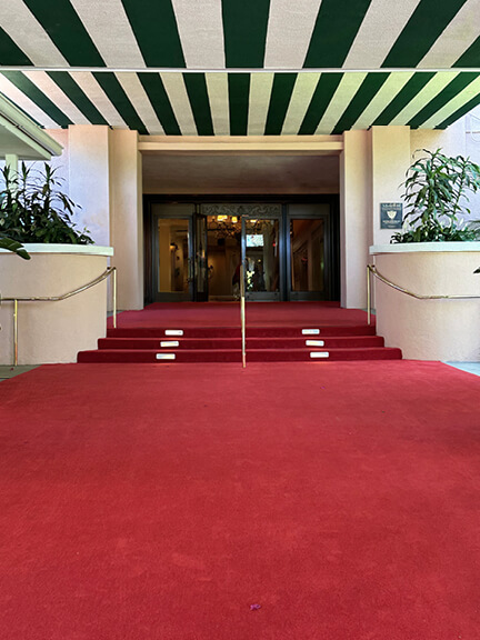Interior view of the Beverly Hills Hotel featuring red carpet and green striped ceiling, highlighting classic historic design.