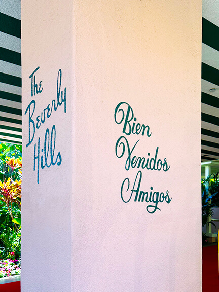 Historic architecture in Los Angeles shown through Beverly Hills Hotel’s iconic signage, pink stucco walls, and classic striped awnings.