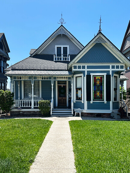 Blue Victorian home in Los Angeles with colorful stained glass windows, showcasing classic details in a historic neighborhood.