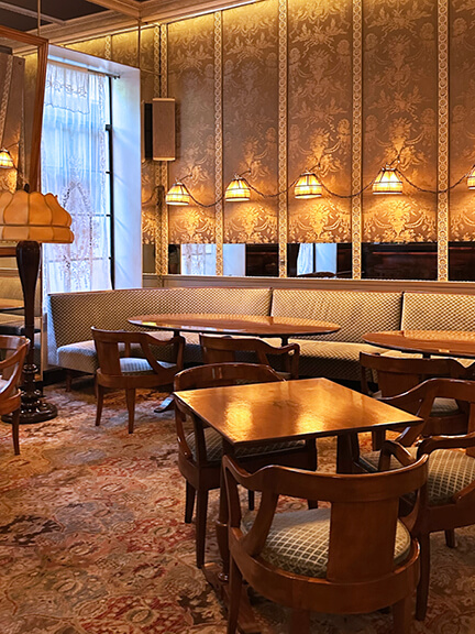 Antique lamps and damask wall pattern in the bar area of Chateau Marmont, reflecting vintage style within historic architecture.