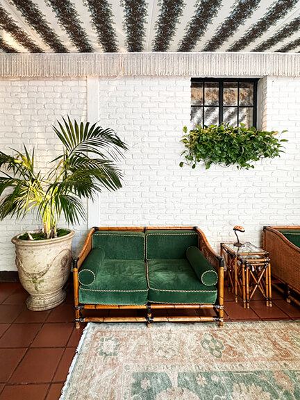 Painted brick entry at Chateau Marmont with a bamboo chair and striped awning, showcasing historic architectural details.