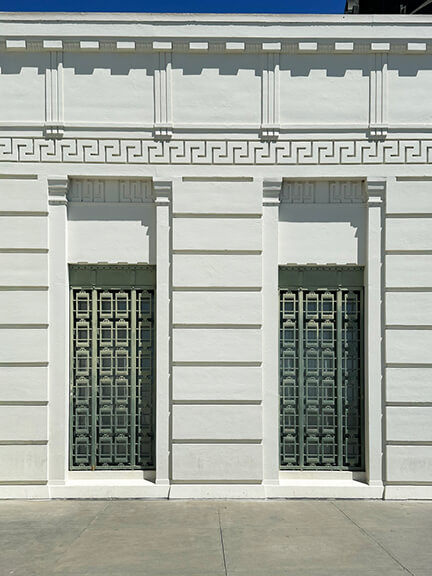 Griffith Observatory’s white facade features metal trellis window coverings and Greek fret detailing across the frieze and entry.