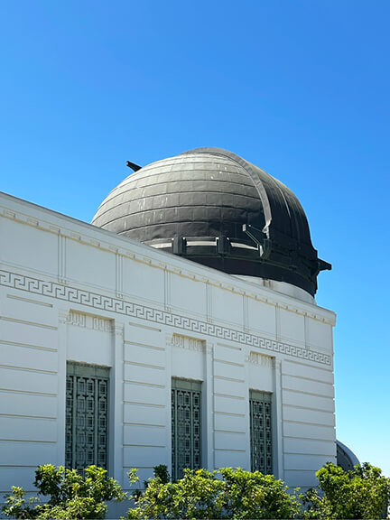 Griffith Observatory with white walls and an aged copper dome overlooking the Los Angeles basin from its iconic hillside location.