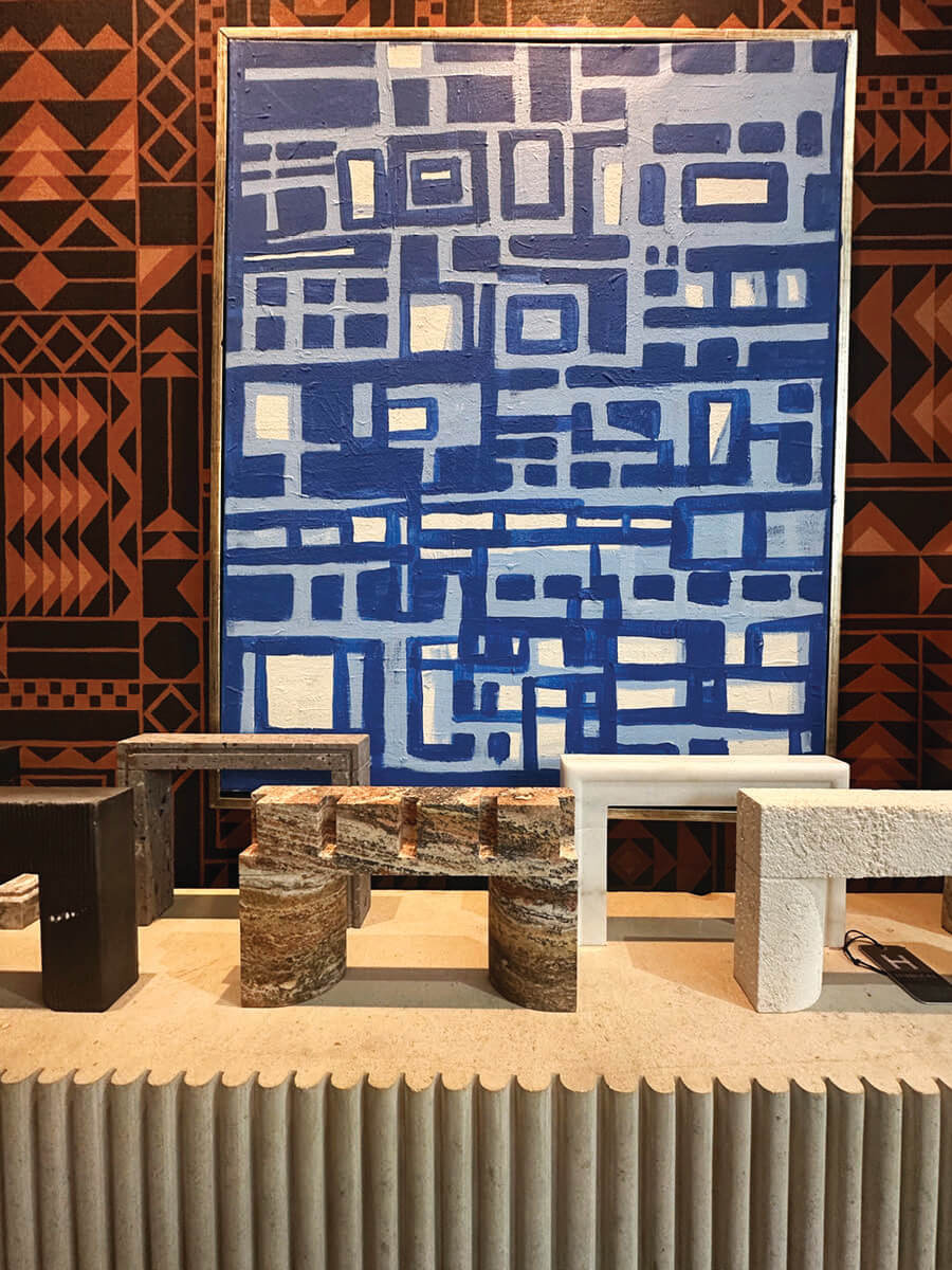 Black-orange geometric wallpaper paired with bold blue art and a limestone fireplace at Harbinger LA showroom