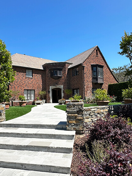Historic architecture in Los Angeles seen in a brick home on South Windsor Boulevard, with diamond-paned windows and manicured landscaping.