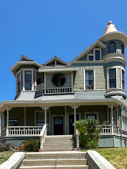 A Victorian home in Los Angeles with off-white trim, a rounded turret, and a covered porch—ornate and full of charm.